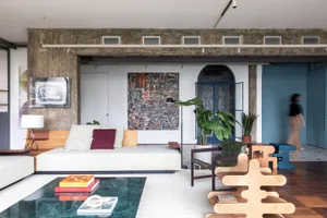 A modern living room features a white sofa with wood accents, artworks on the wall, plants, and a glass coffee table.