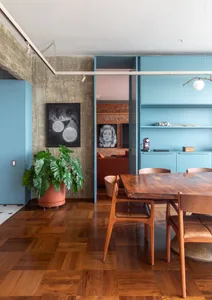 A modern living room with wooden floors, blue cabinets, and a potted plant.
