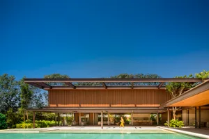 Modern residential exterior with a pool, featuring wood, glass, concrete, and metal materials.