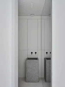 A modern bathroom with two granite pedestal sinks and black faucets.