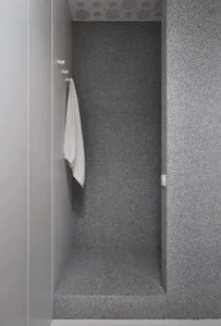 A modern bathroom with gray and concrete walls, featuring a towel hanging on a hook.