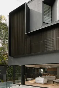 Modern, minimalist house exterior with large black windows and wooden shutters.