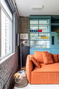 A modern industrial living room featuring an orange sofa, glass shelves, and a textured wall.