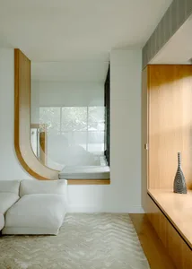 Modern living room with white sofa, wooden shelves, and window seat