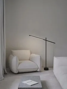 A modern living room with a concrete floor, a white armchair, a black floor lamp, and a granite table.