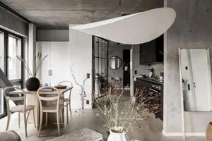 A modern living room, dining room, and kitchen with concrete walls and wooden furnishings.