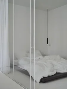 A minimalist bedroom with a bed in the center and a white curtain.