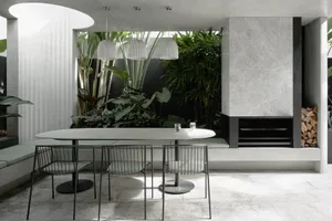 A modern minimalist outdoor dining area with concrete walls and a fire pit.