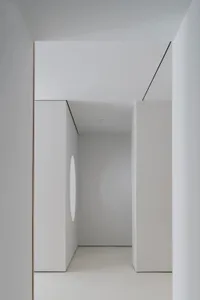 A minimalist modern living room with white concrete walls and a circular cut-out feature.