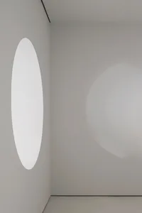 A minimalist design featuring a glass space with a circular window.