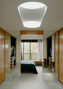 A modern indoor space featuring illuminated wooden cabinets and a ceiling light fixture, showcasing contemporary interior des