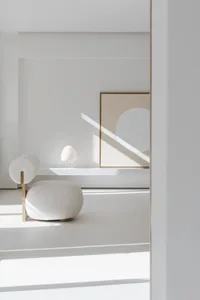 Modern minimalist living room with a white upholstered chair and a white lantern lamp on a white shelf.