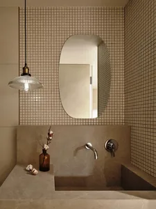 A minimalist bathroom with concrete walls, a tiled floor, and a glass pendant light fixture.