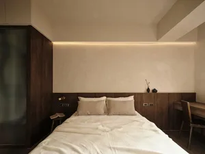 Modern minimalist bedroom with wood paneling on the wall and ceiling, featuring a bed with white bedding, a small table, and