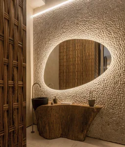 Modern bathroom featuring a stone wall with an oval-shaped mirror and a wooden vanity.