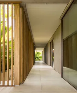 A modern corridor featuring wooden walls and floors with a view of greenery outside.