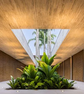 A modern architectural interior with concrete walls, bamboo materials, and a garden featuring lush green plants.