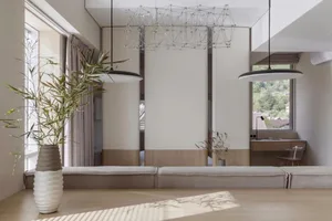 A modern living room with wooden furniture, a large window, and decorative plants.
