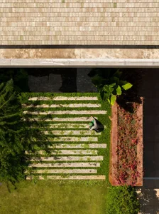 A modern landscape design featuring grass, stone pathways, and wooden structures.