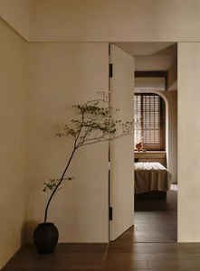 A minimalist bedroom with a bed, bedside table, and wooden floor and walls.