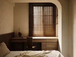 Modern minimalist bedroom featuring wooden blinds and a wooden desk with a chair.