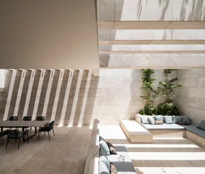 A modern minimalist living space featuring light-colored tiles and marble materials.