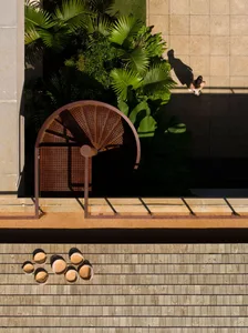 A modern outdoor space featuring a wooden spiral staircase, metal railings, and concrete paving.