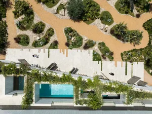 A modern residential exterior with a concrete facade and rock pathway.