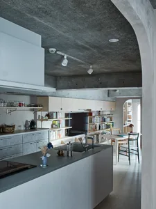 A minimalist kitchen with concrete countertops and a concrete ceiling.