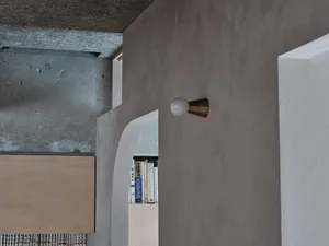 A minimalist interior space with concrete walls and a simple lamp.