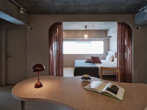 A modern residential interior with concrete walls and soft textiles.