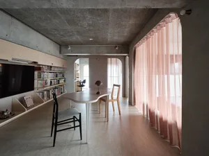 A modern home office space featuring concrete and stone materials with a large curtain for privacy.