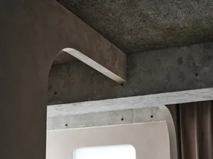 A close-up view of a modern interior featuring a smooth, concrete arch with a textured ceiling and wall.