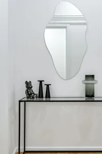 A minimalist console table displaying modern decor items, including a glass vase, a black bear figurine, and two black candle