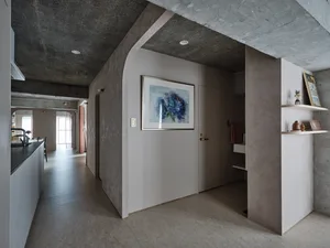 Modern, minimalist residential interior with concrete and plaster walls and a white door with artwork.