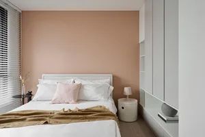 Modern minimalist bedroom with white furniture and a brown blanket on the bed.
