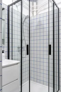 Modern minimalist bathroom featuring ceramic tiles, sleek glass shower enclosure, and integrated vanity unit.