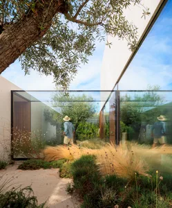 A modern residential garden featuring glass walls and wooden elements.