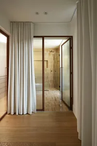 A minimalist bathroom with tiled walls and floor, featuring a frosted glass partition and a metal-framed glass door.