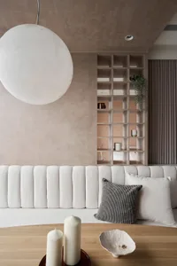 A minimalist living room with concrete walls, a white sofa, and a wooden coffee table with candles and bowls.