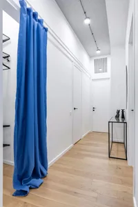 Modern closet with blue curtain, white walls, and white flooring.