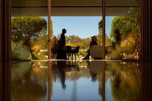 A modern residential building with large glass windows reflecting the surrounding nature.