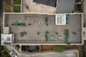 Aerial view of a modern wooden patio with potted plants, outdoor furniture, and a transparent glass wall.