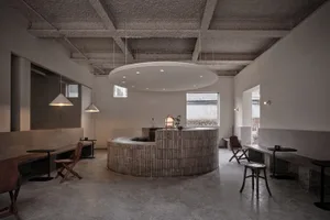 Industrial-style coffee shop interior with wooden panels, concrete floor, and modern seating options.