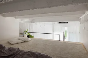 Industrial-style bedroom with concrete framing, a potted plant, and minimalist decor.
