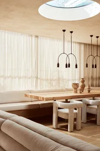 Neutral-toned minimalist residential interior with a long wooden table and upholstered furniture.
