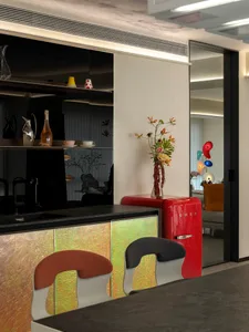 現代極簡廚房，配有紅色金屬冰箱、吧台椅與黑色檯面。