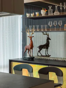 A modern bar with black metal deer statues on the counter, illuminated by ambient lighting, and adorned with glassware and de