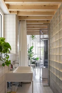 Modern bathroom with glass shower enclosure, white tiles, and wooden accents.