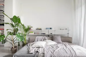 A bedroom with a modern design featuring a brown wooden bed and grey fabric bedding.